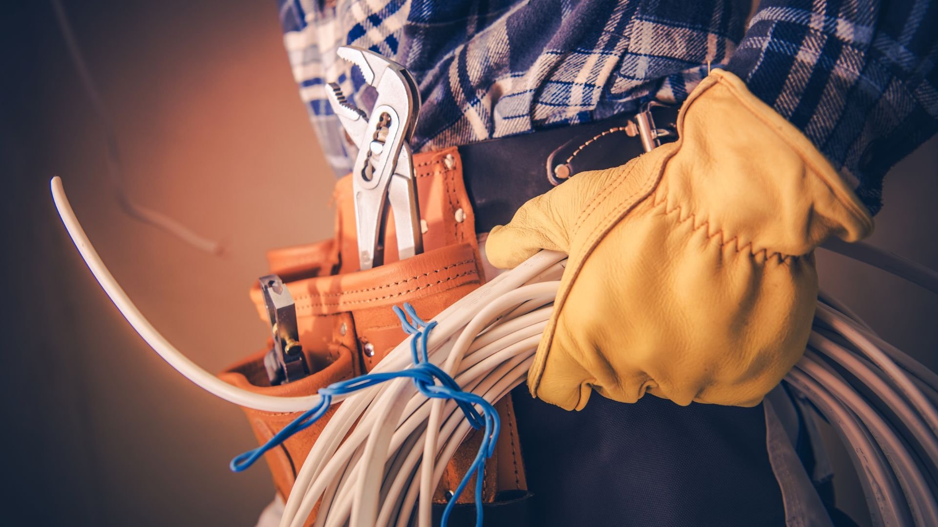 Electrician's tool belt with pliers, cables, and protective work gloves