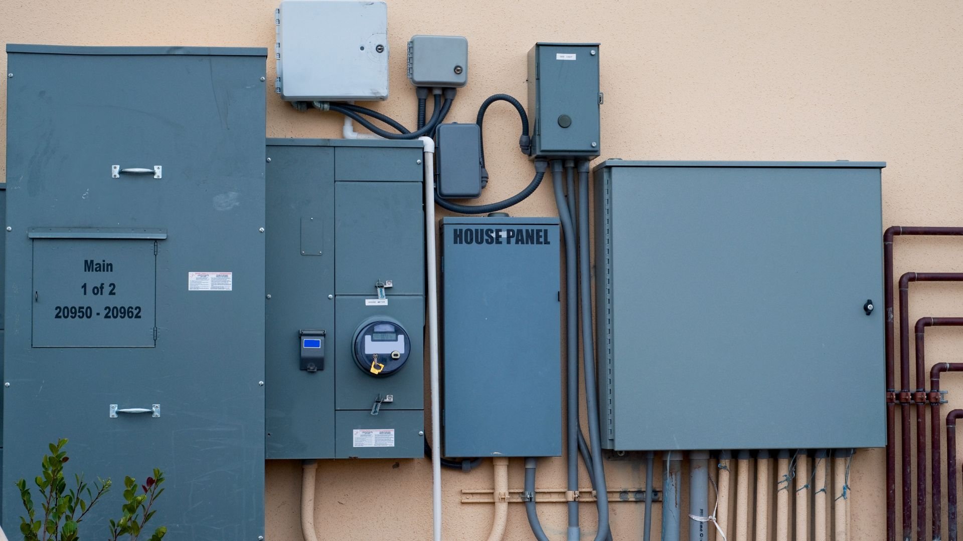 Electrical panels and meters mounted on exterior wall with cables and conduits