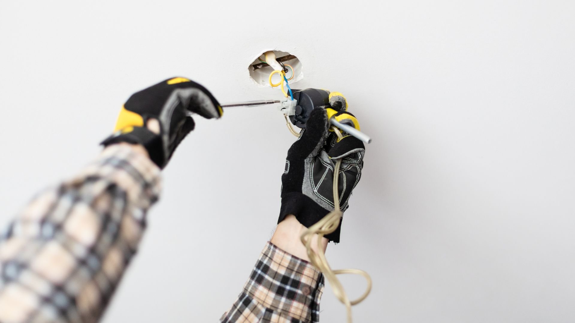 Robotic hand in black and yellow gloves connecting electrical wires